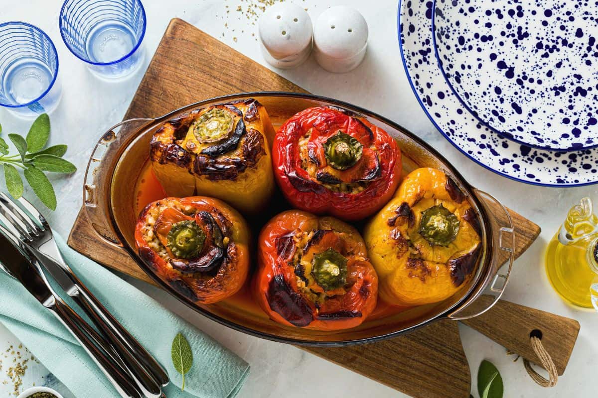 Baked stuffed bell peppers filled with a colorful vegan mixture and served in a baking dish.