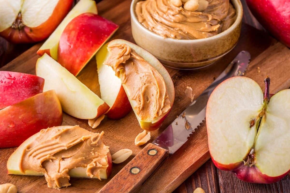 Apple slices served with creamy almond butter on a wooden board.