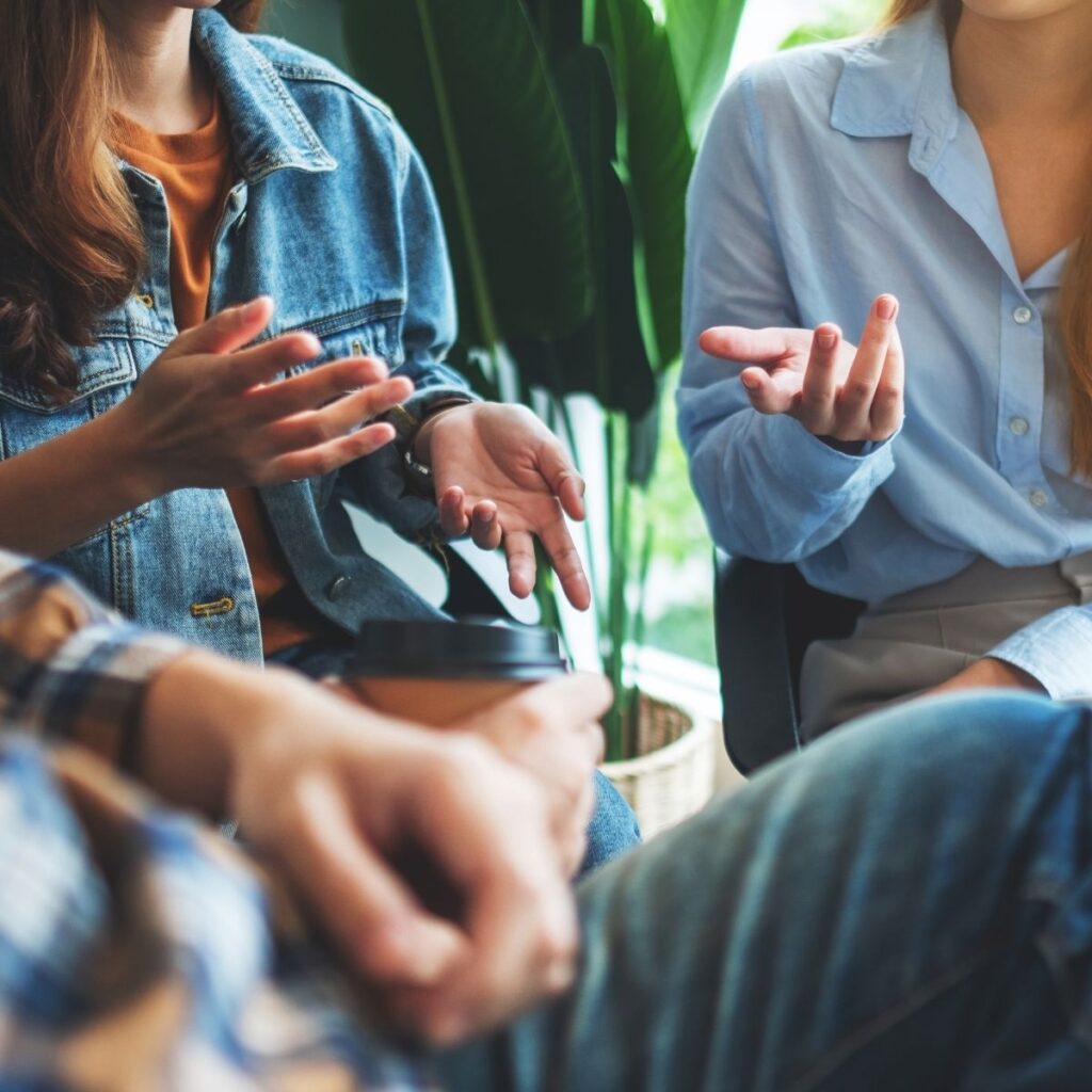Group of people sitting together and having a conversation in a casual indoor setting.