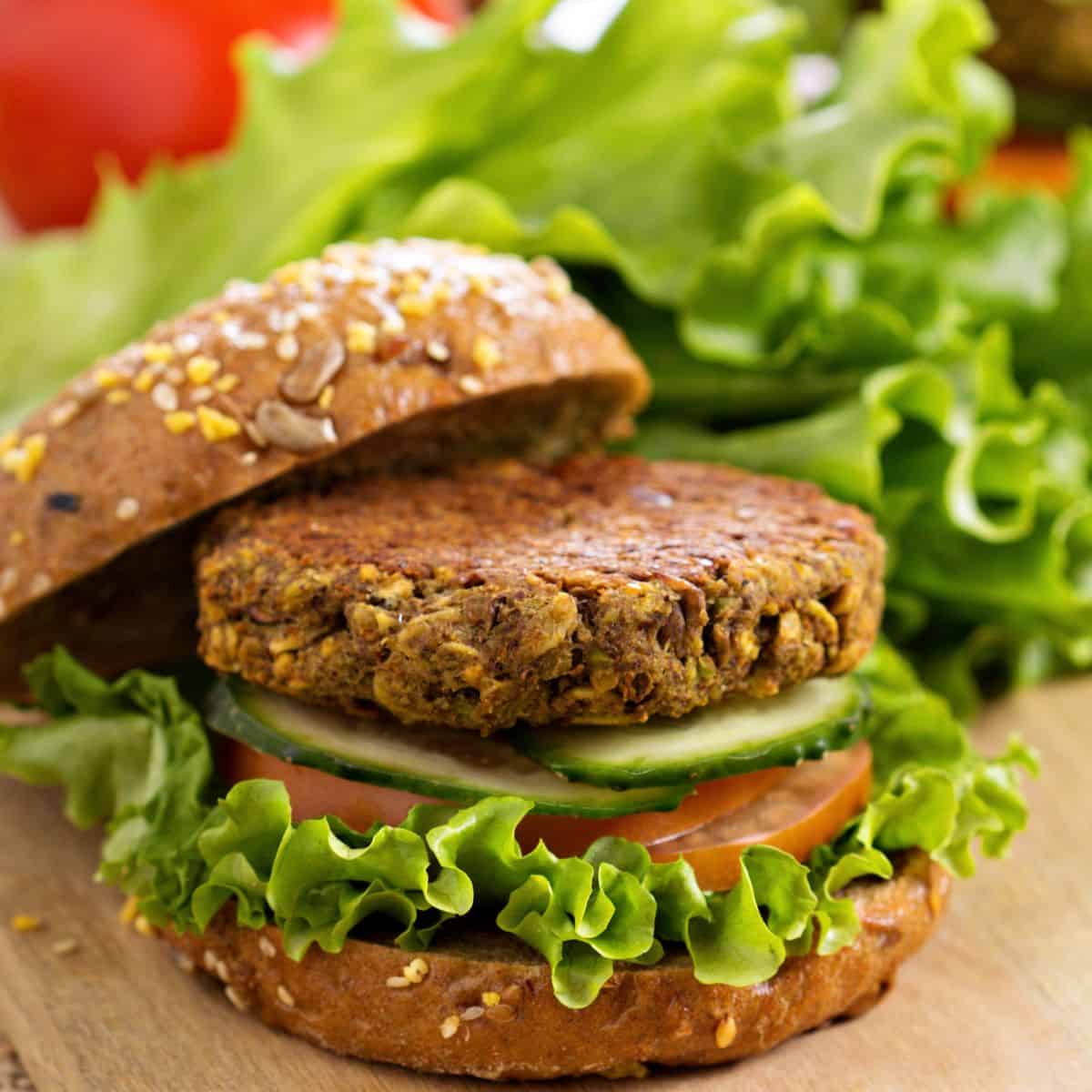 Plant-based burger with a vegetable patty, lettuce, tomato, and cucumber on a whole grain bun.