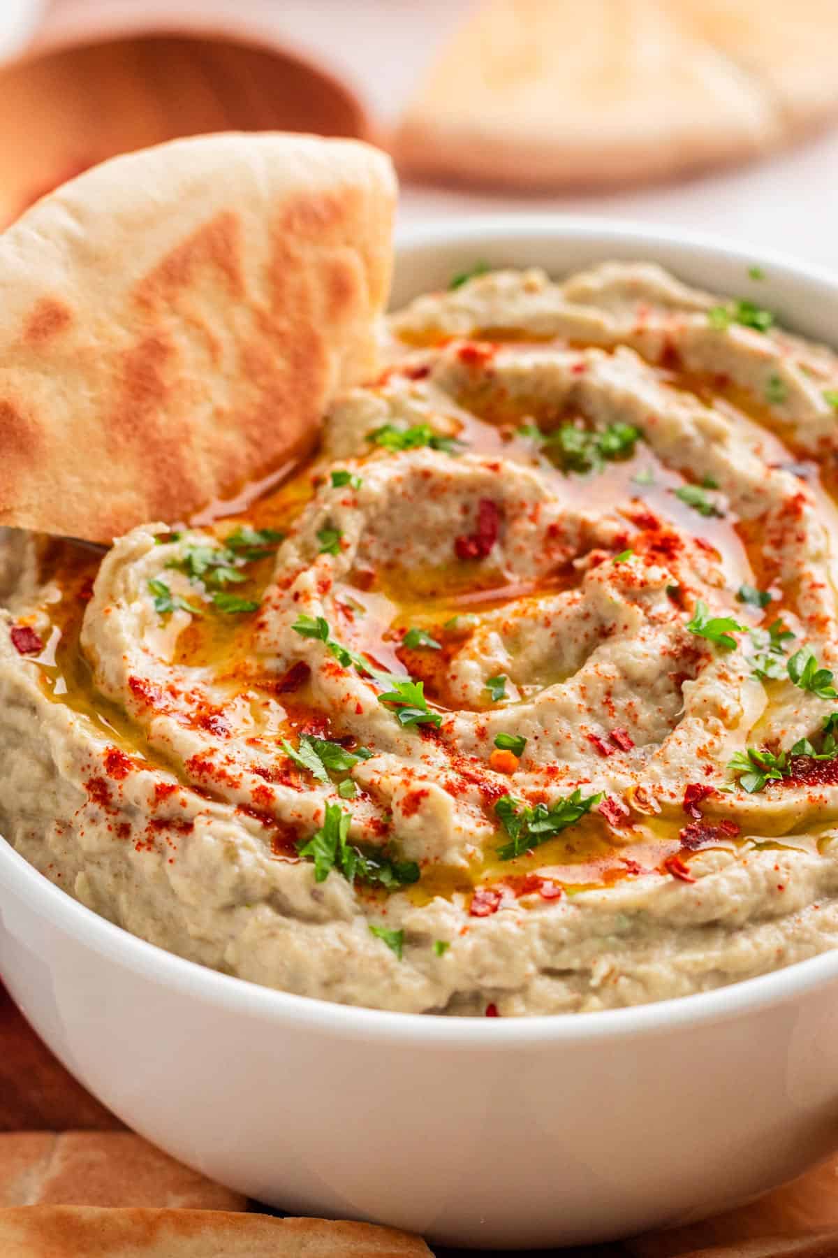 Eggplant baba ganoush spread in a bowl with pita and dippers.