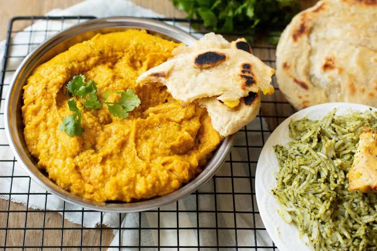 Vegan curry served with flatbread and rice on a restaurant-style table.