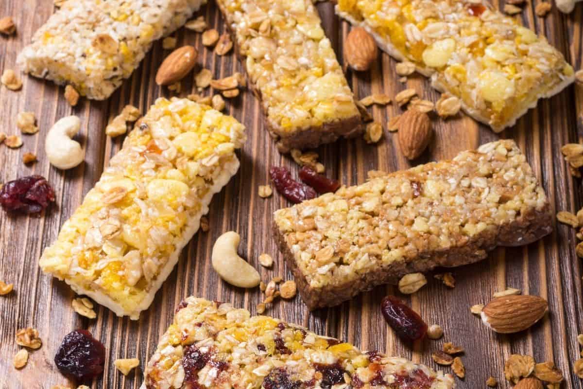 Assorted vegan granola bars with nuts, seeds, and dried fruit on a wooden surface.