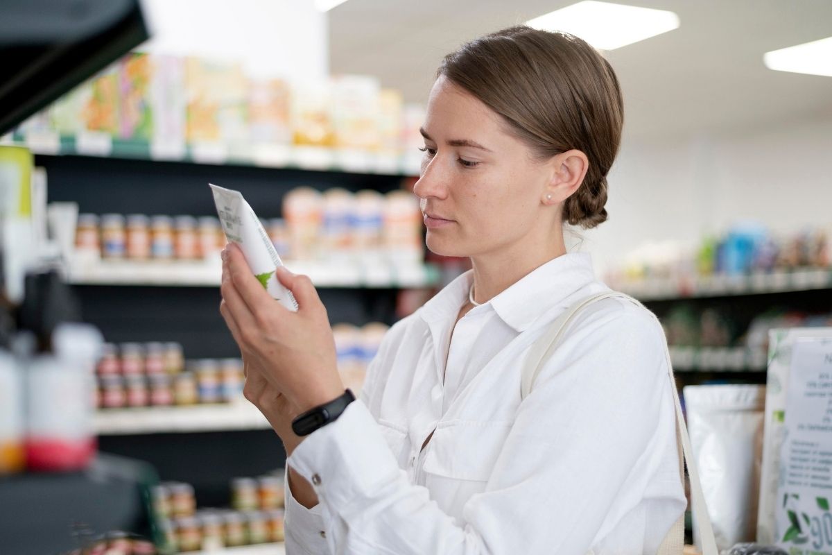 Woman reading the label on a skincare product while shopping in a store.