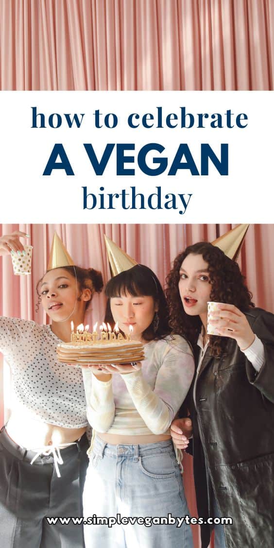 Three women celebrating a birthday, wearing birthday hats, with one holding a birthday cake. Two of them are holding party cups. They are standing in front of a pink curtain background with text in the center that says "How to Celebrate a Vegan Birthday."