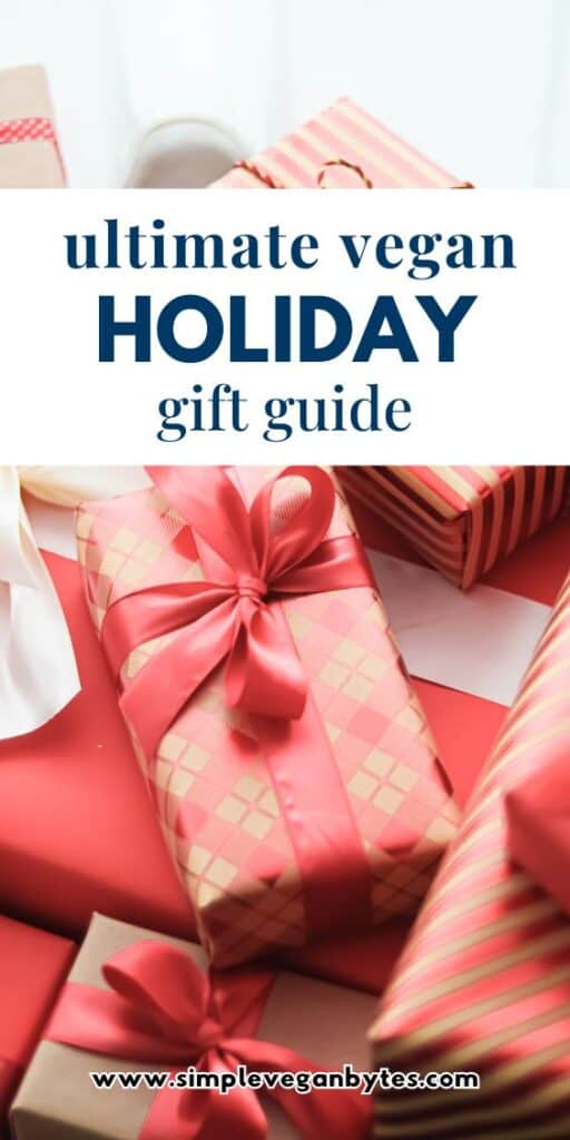 A high-angle close-up of several gifts wrapped in red and gold patterned paper with satin ribbons. A white text banner in the center reads "ultimate vegan holiday gift guide"