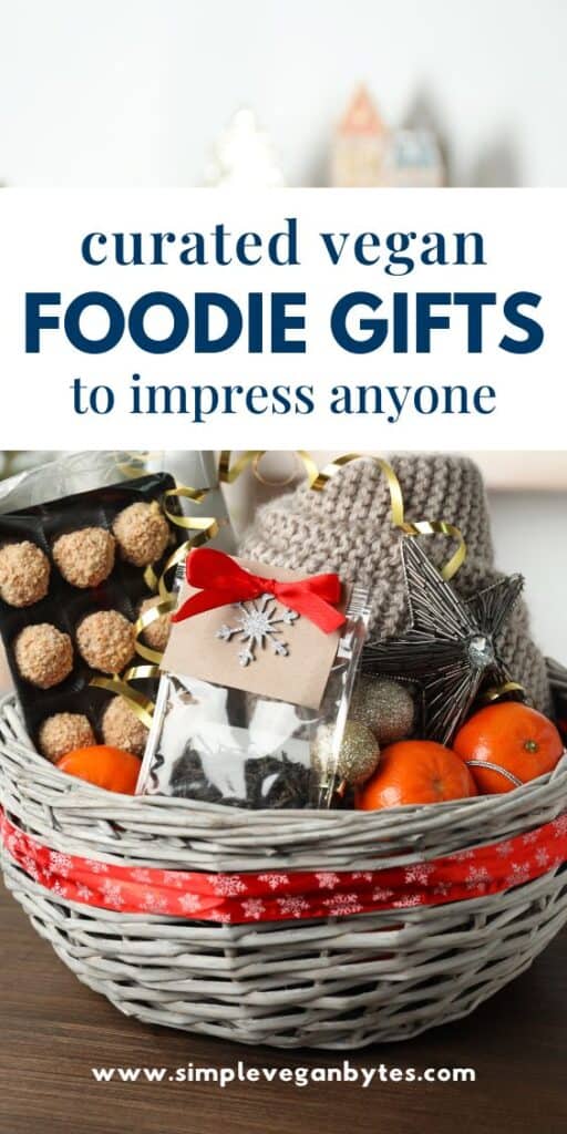 A festive holiday gift basket filled with vegan treats, including a box of nut-covered truffles, a bag of loose tea with a red bow, fresh clementines, and a cozy knit item. The text above reads "curated vegan foodie gifts to impress anyone."