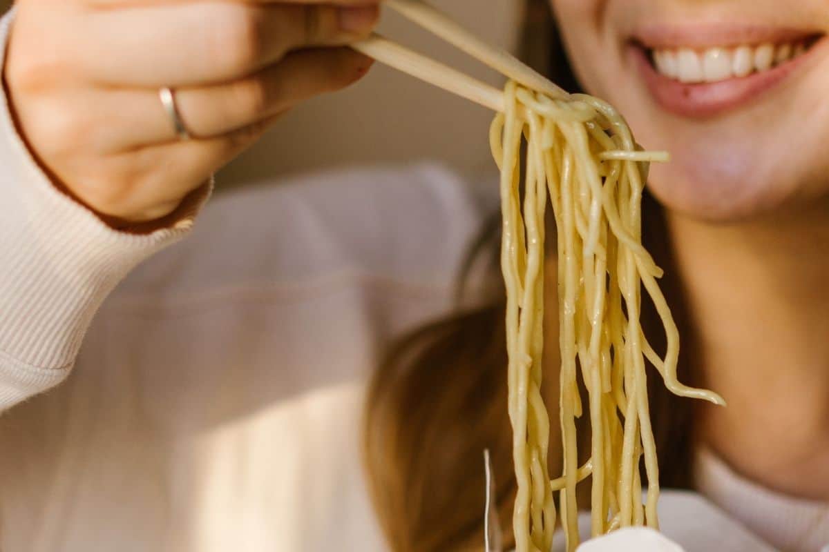 Woman happily smiling while eating noodles