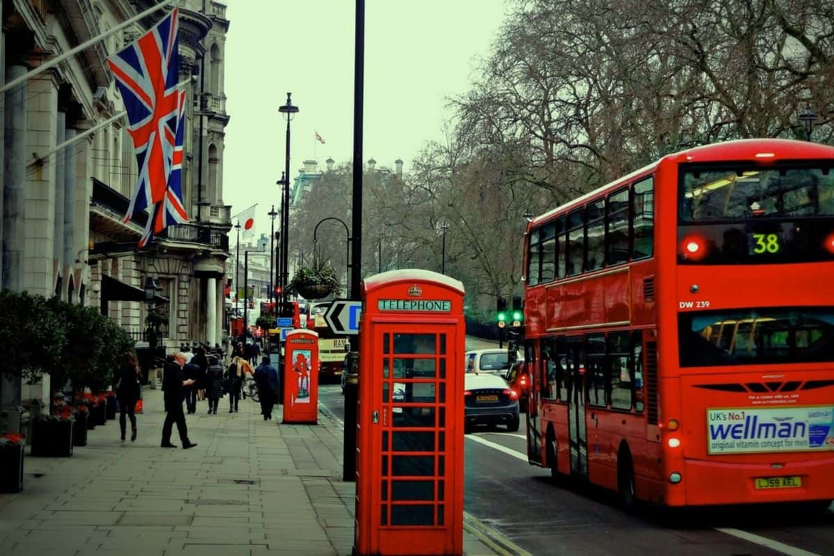 A red double-decker bus and a traditional red telephone booth on a London street with Union Jack flags