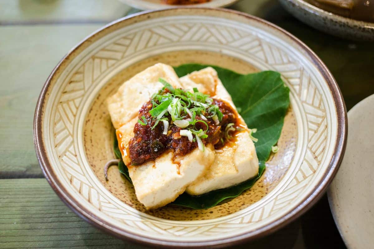 Soft tofu with sauce and fresh herbs served on a plate