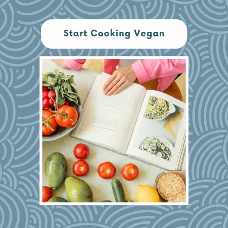Open cookbook on a kitchen table surrounded by fresh vegetables and plant-based ingredients.