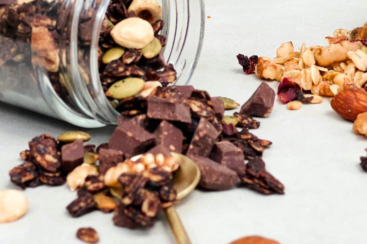 Vegan chocolate and nut snack mix spilling from a jar