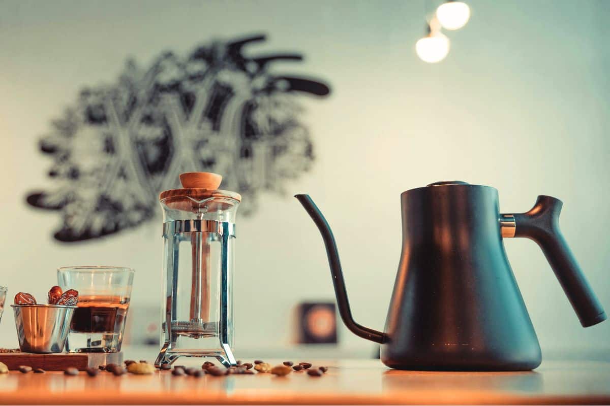 Pour-over coffee kettle and French press coffee maker on a kitchen counter.