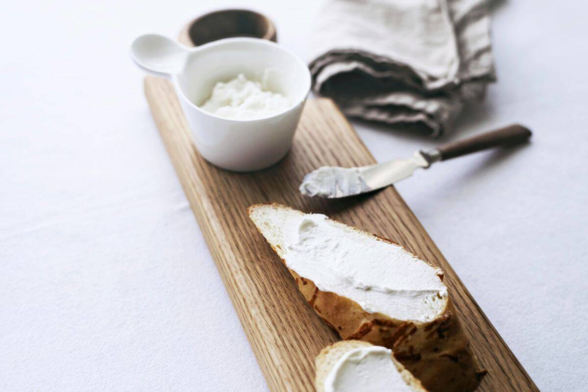 Cashew cheese spread on bread with a small bowl of vegan cheese.