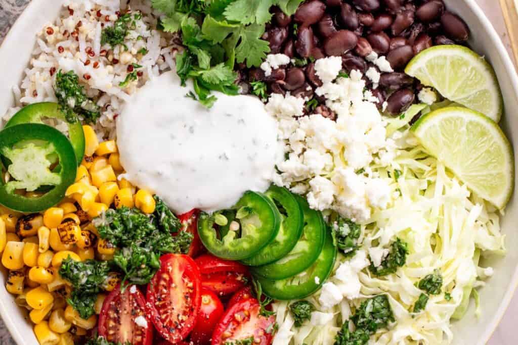 Vegan burrito bowl with rice, beans, avocado, corn, and fresh veggies