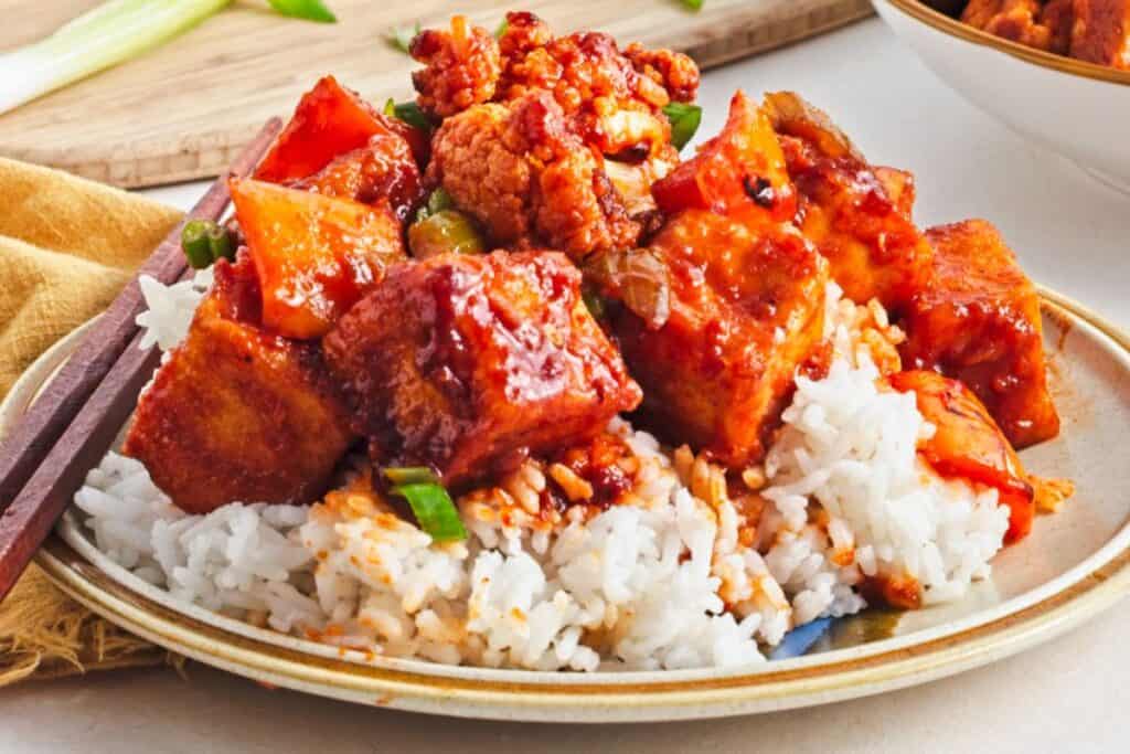 Sweet and spicy tofu served over rice with sauce and green onions