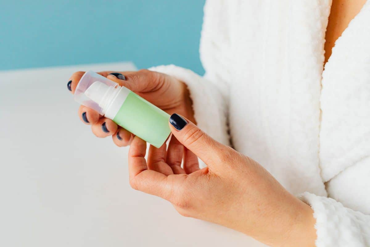 Hands holding green skincare pump bottle