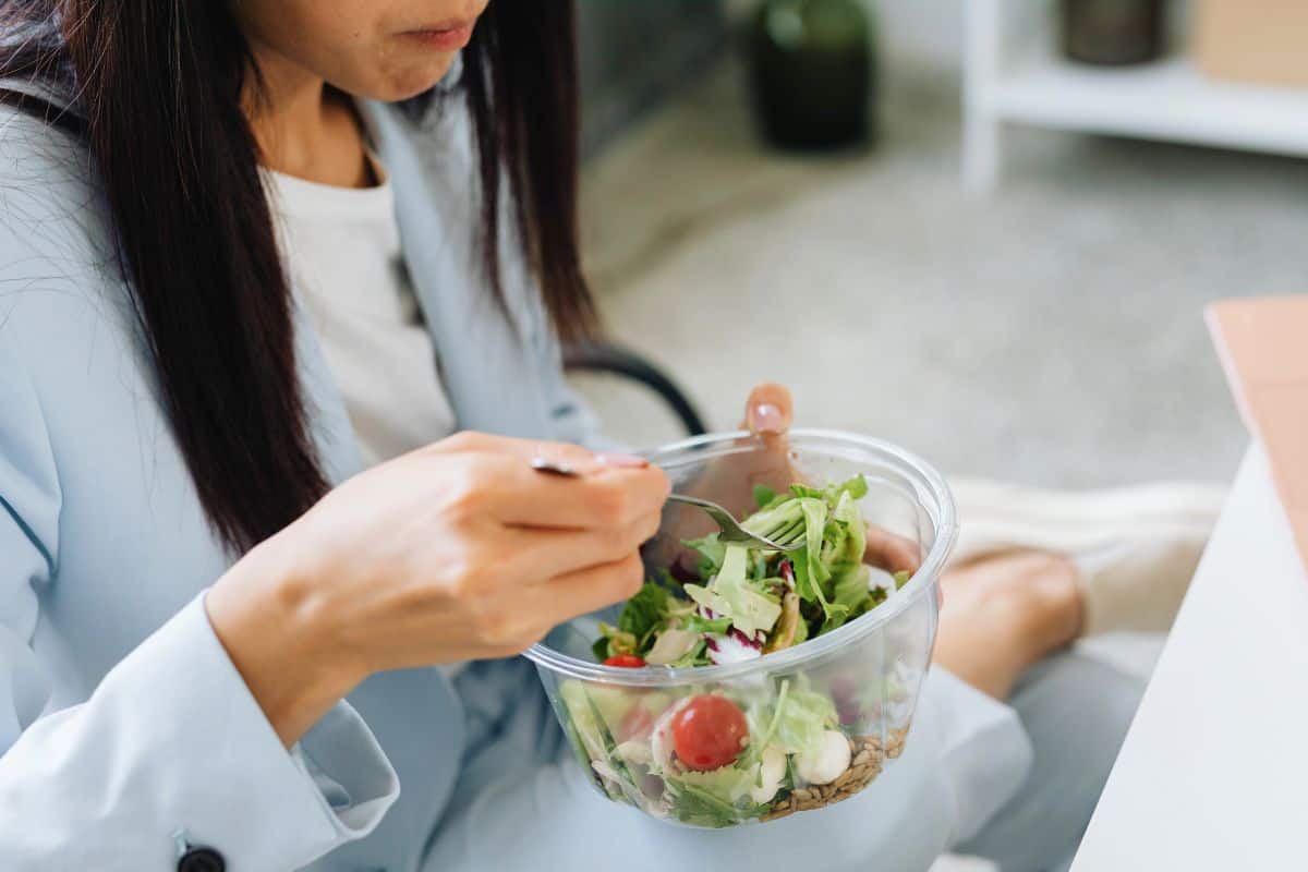 Woman eating a fresh salad while sitting on the floor