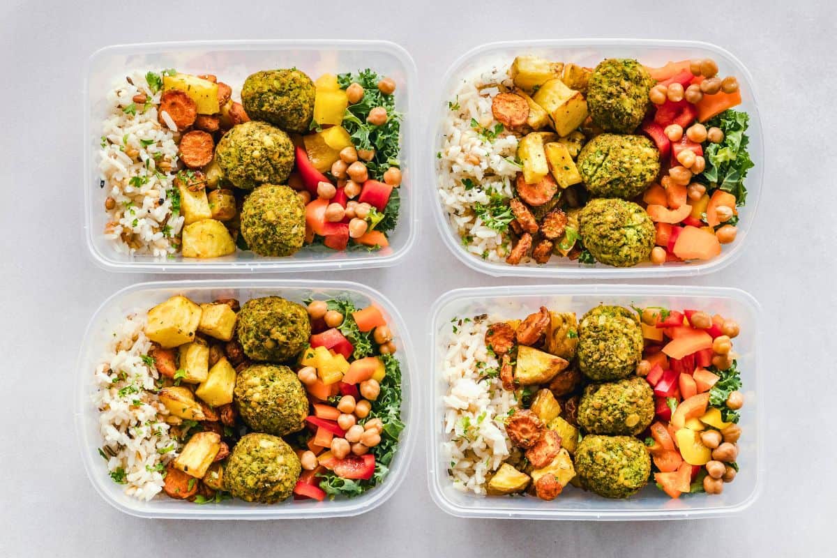 Vegan meal prep containers with rice, vegetables, and falafel