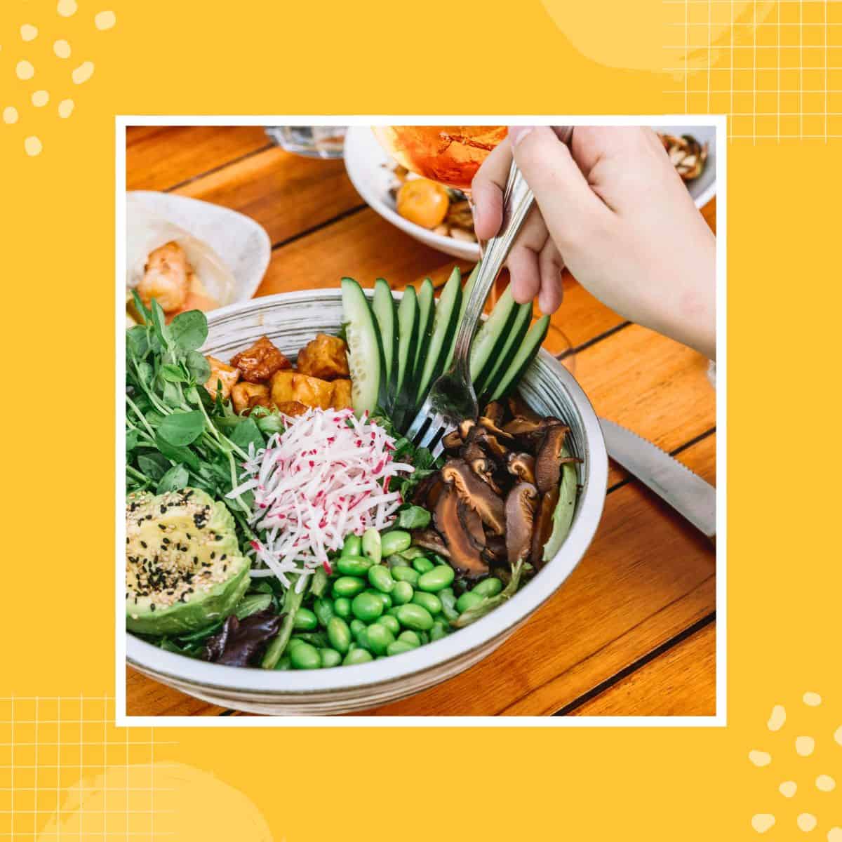Person eating a vegan bowl with avocado, mushrooms, and edamame