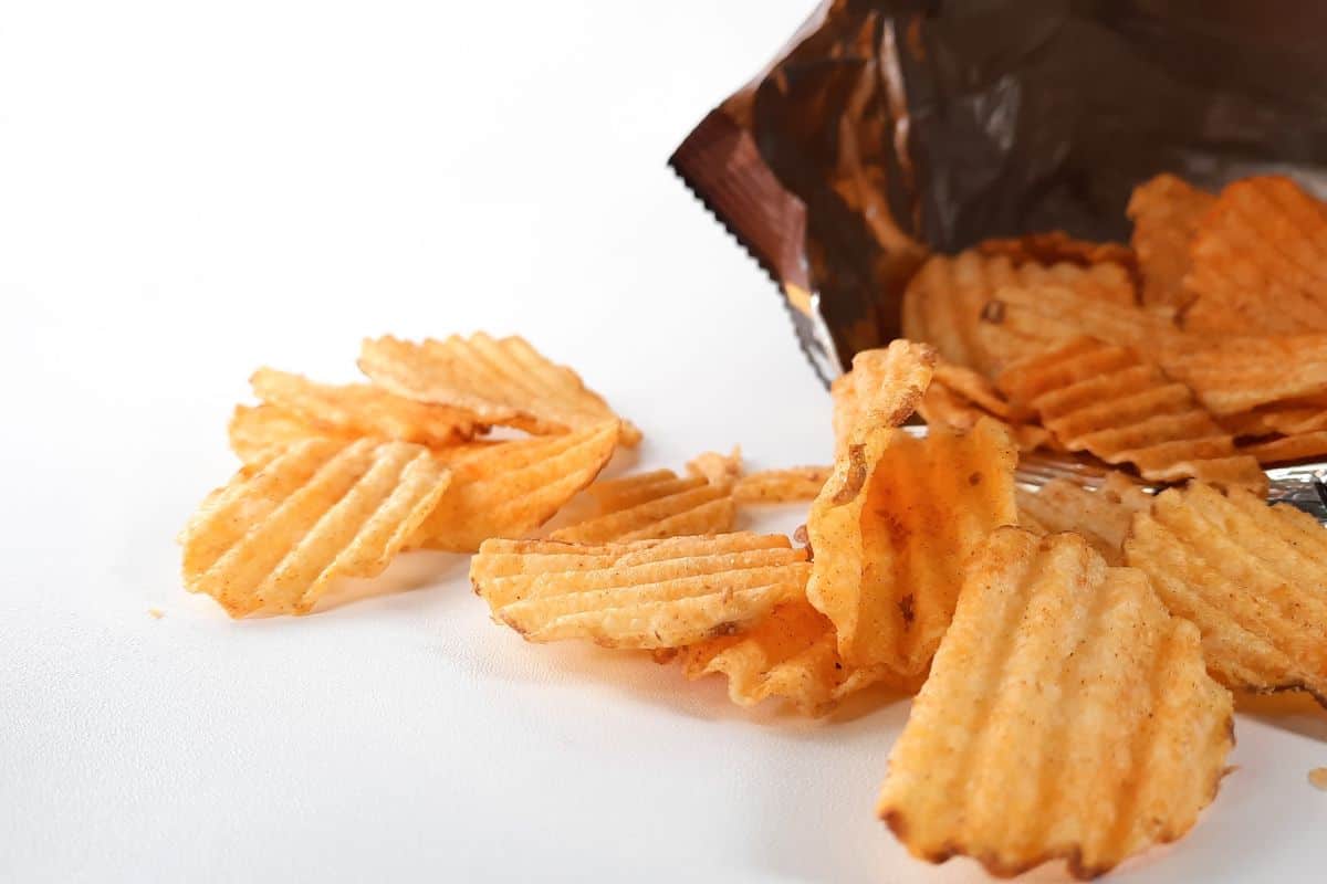 Ridged potato chips spilling from an open snack bag