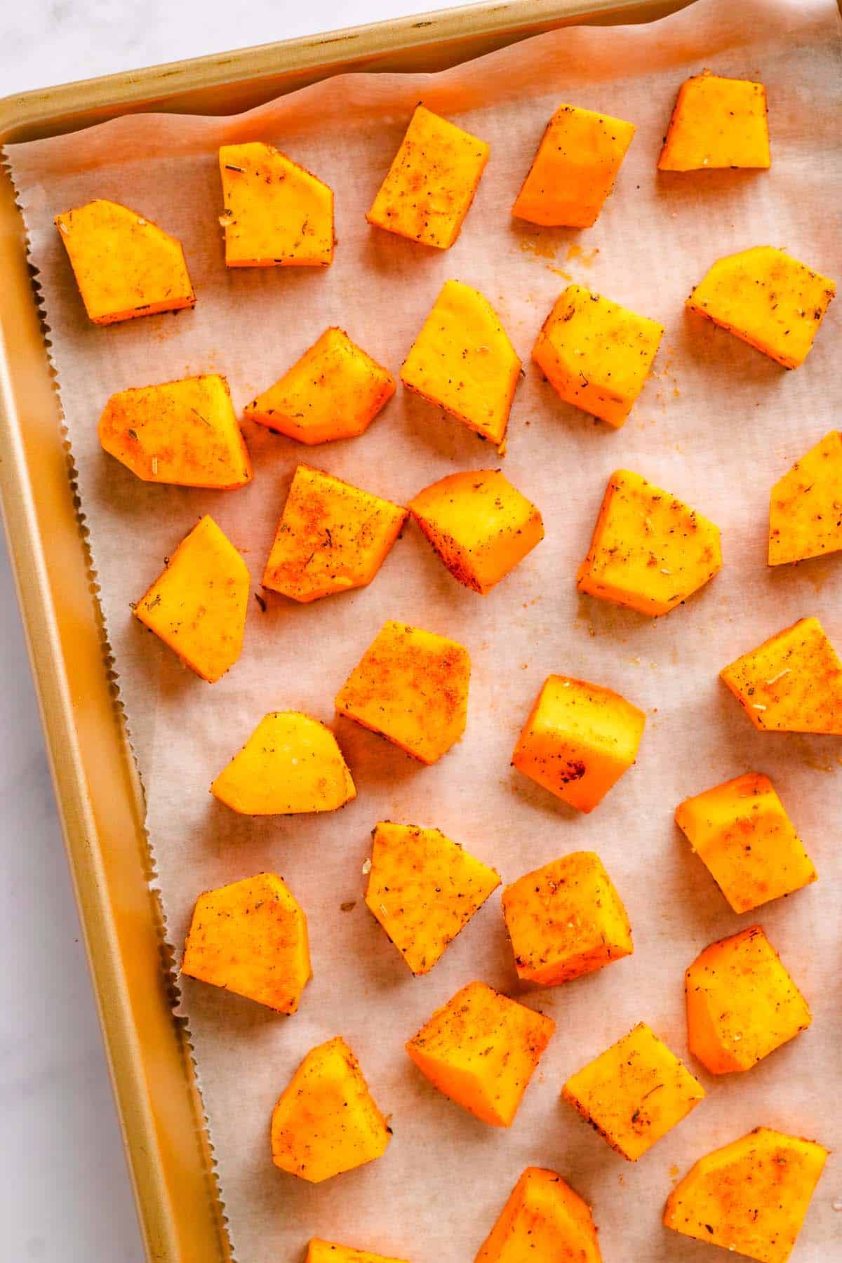 Roasted sweet potatoes spread on a lined baking sheet