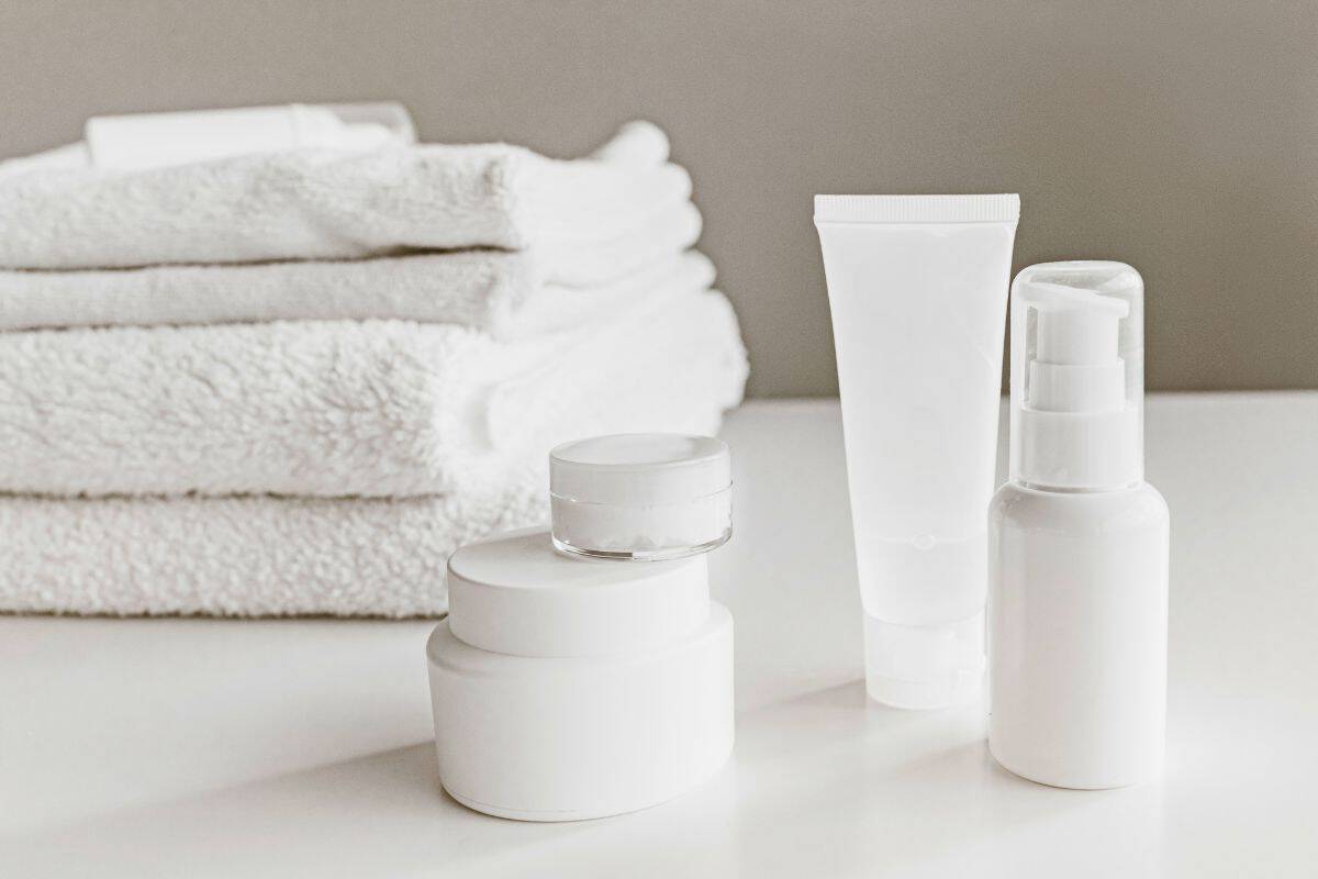 Simple white skincare bottles beside folded towels
