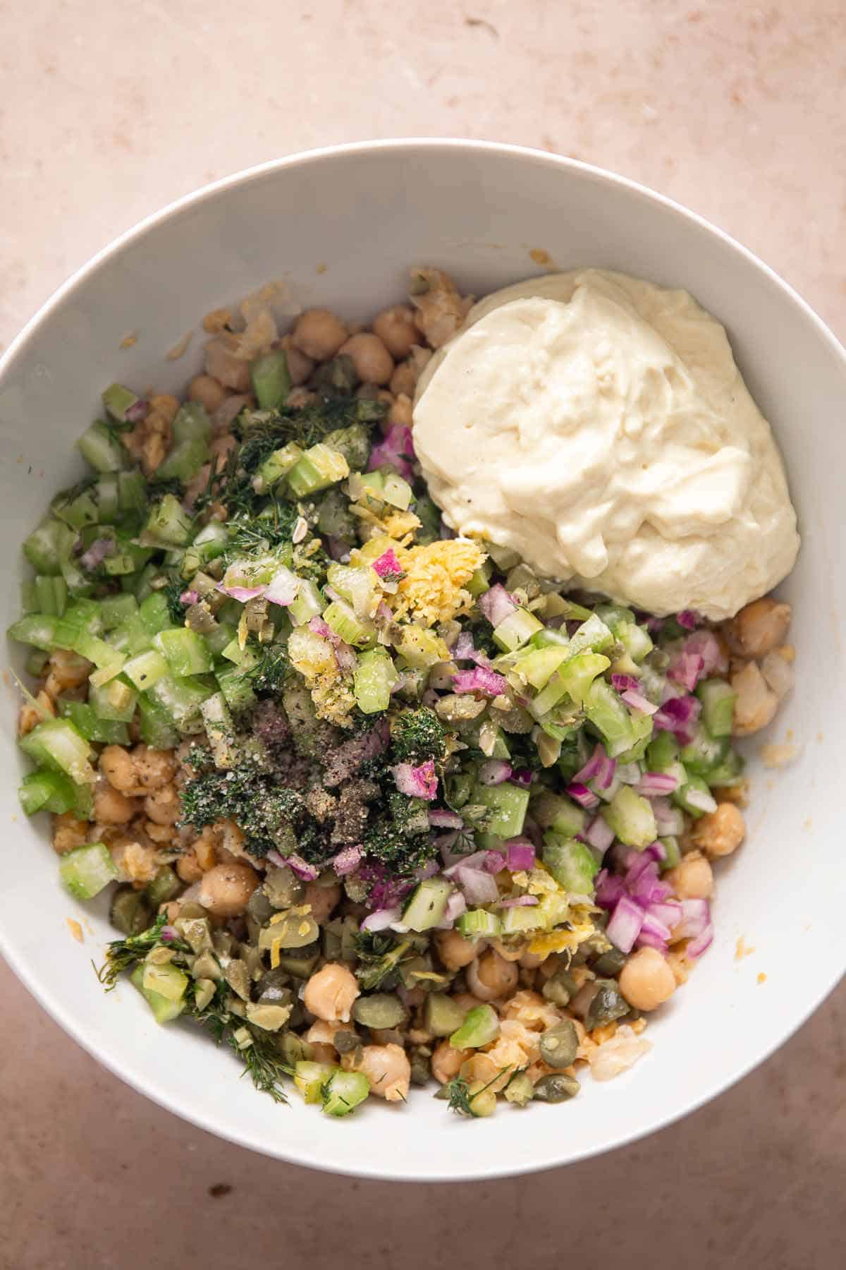 Chickpea salad ingredients mixed with vegan mayo in a bowl