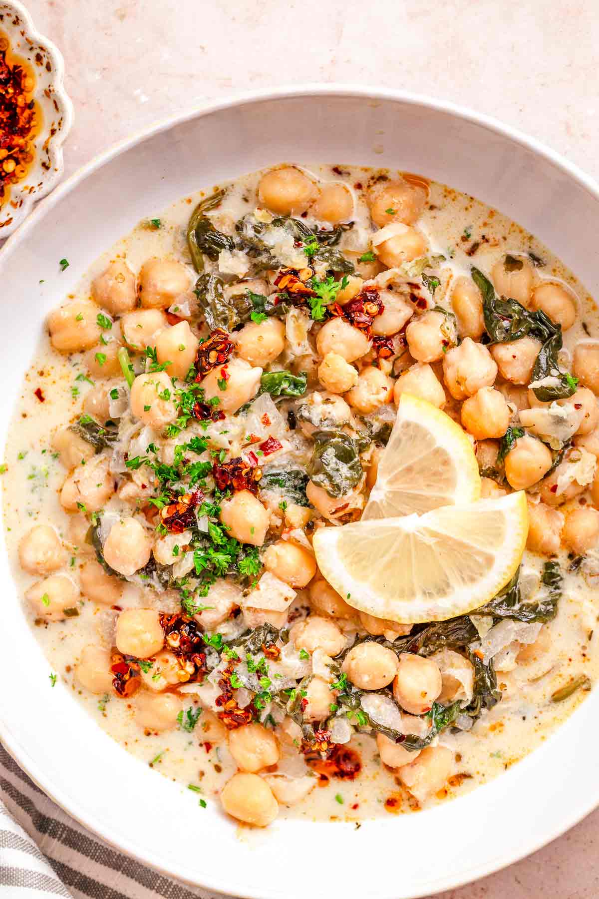 Creamy lemon chickpea stew topped with chili oil, parsley, and lemon slices