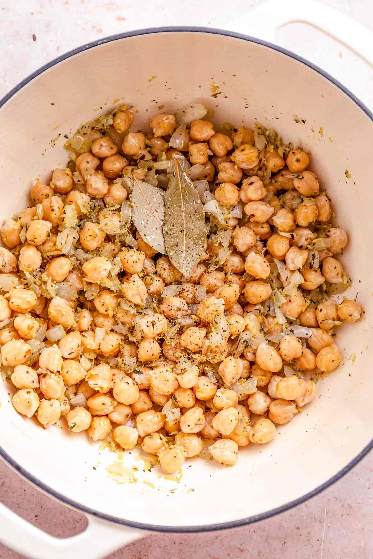 Chickpeas cooking in a pot with herbs and bay leaves