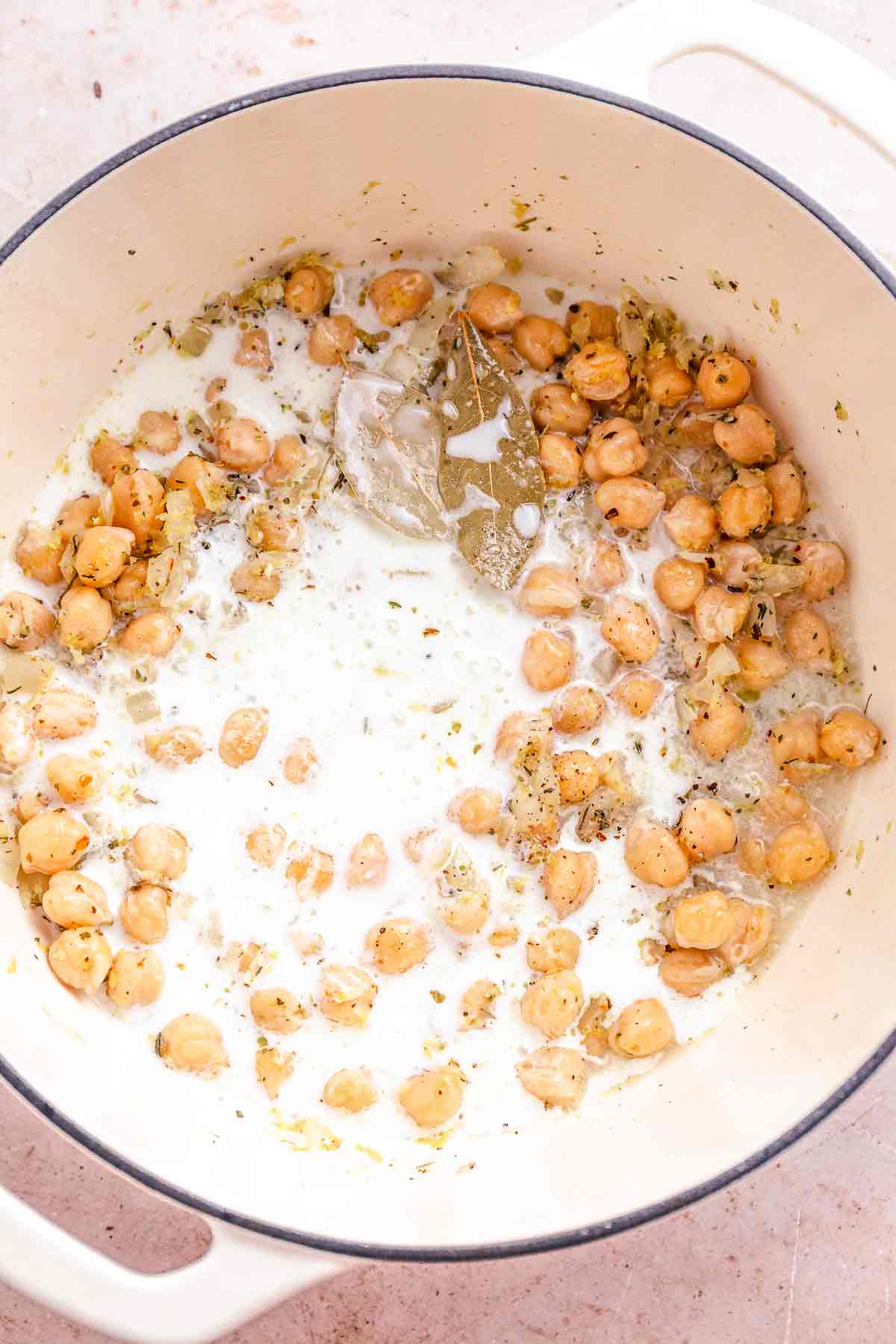Coconut cream added to chickpeas in a pot before simmering