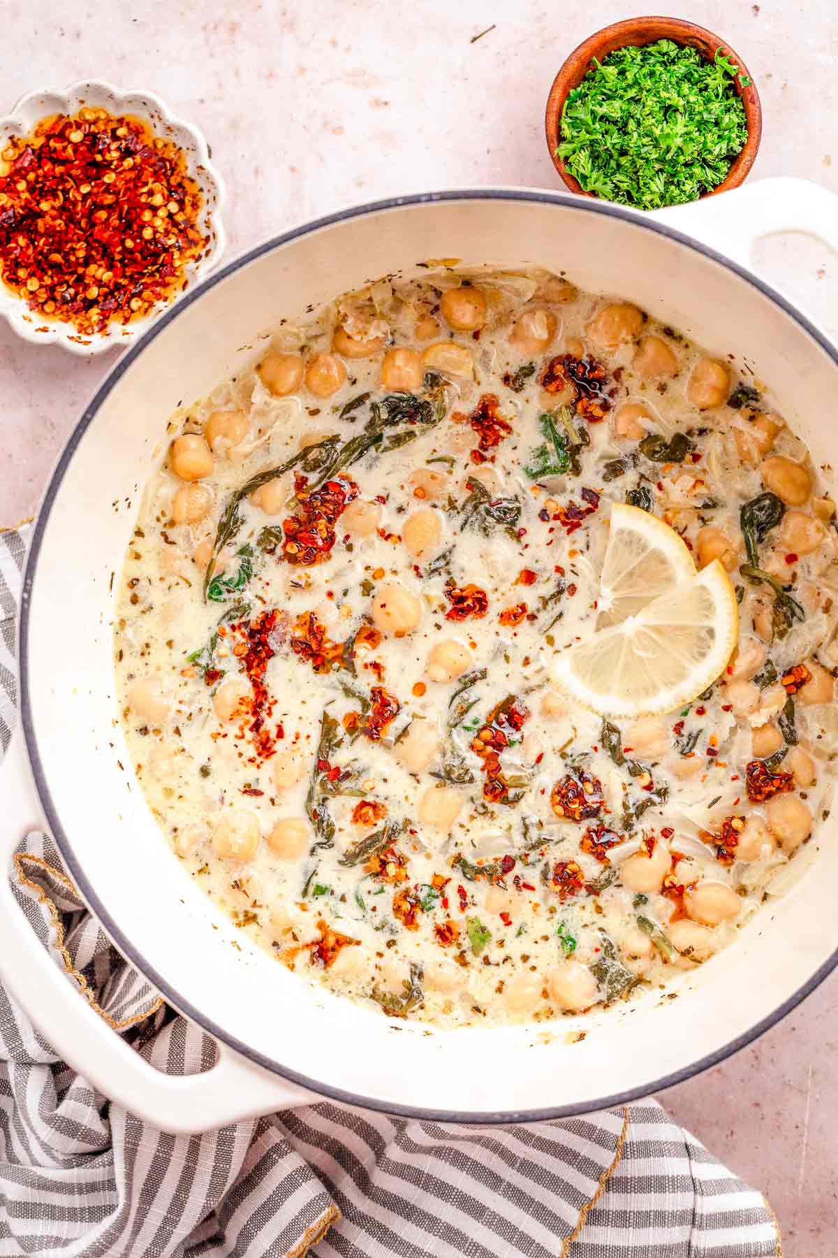 Large pot of creamy chickpea stew topped with chili oil and lemon slices