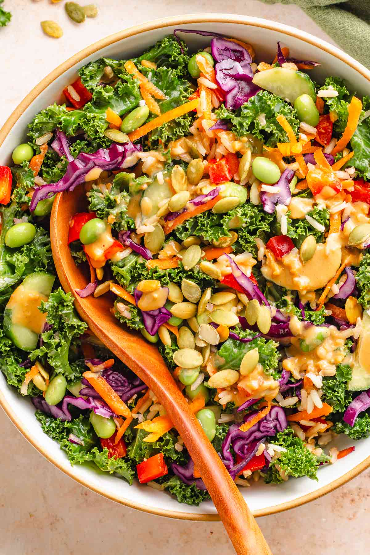 Vegan kale salad with miso dressing topped with pumpkin seeds and edamame