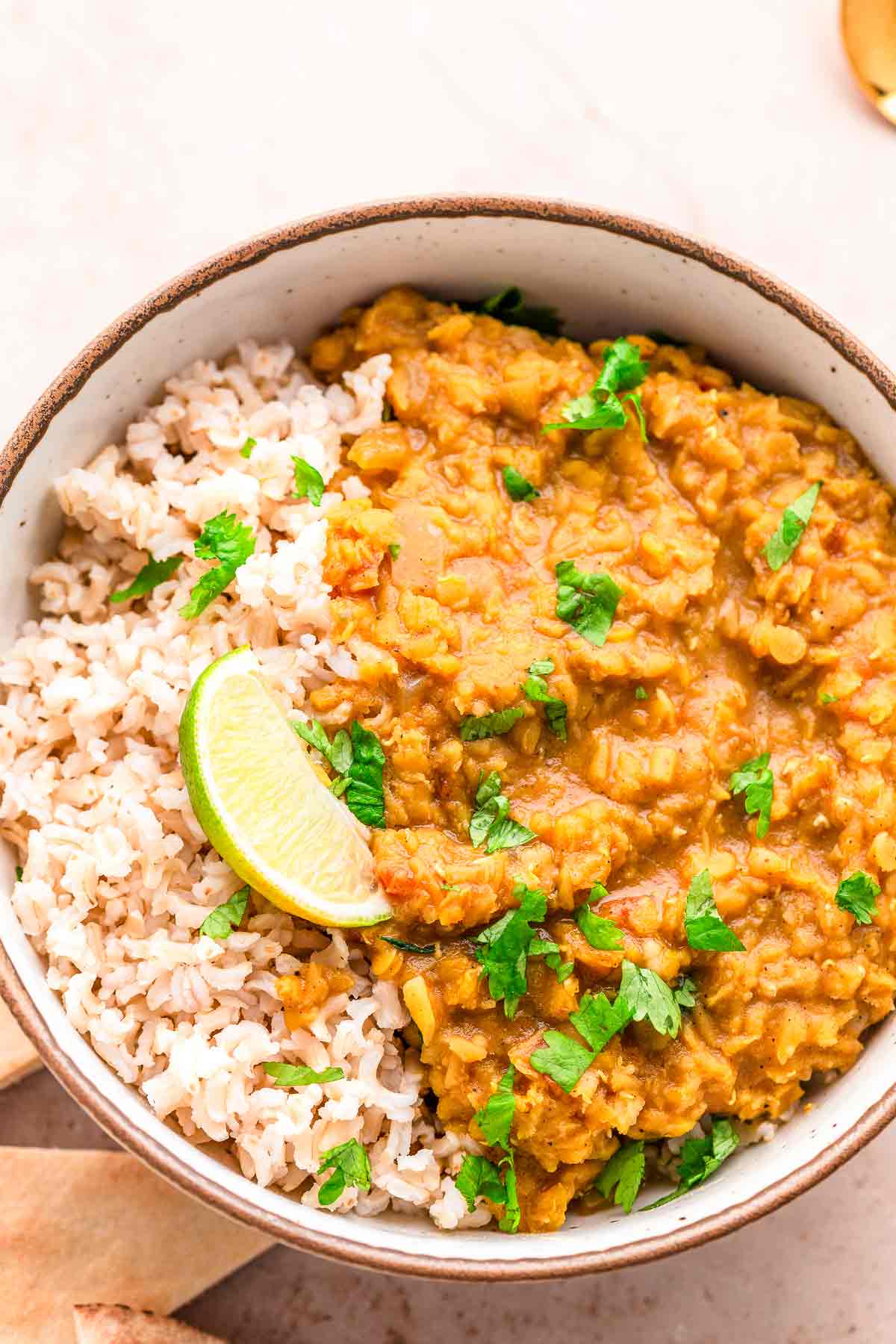 Creamy lentil dhal served with rice, lime wedge, and cilantro