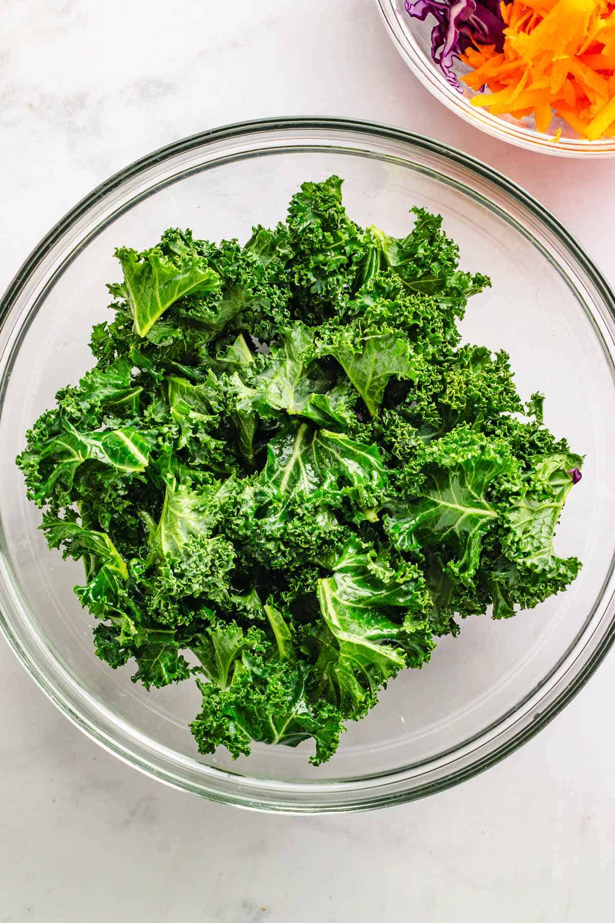 Massaged curly kale in a glass bowl ready for salad prep