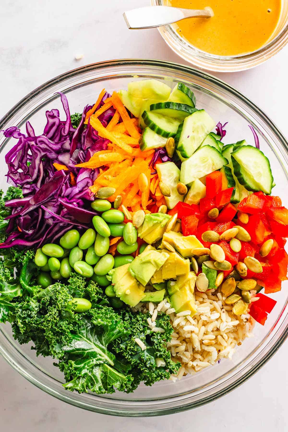 Kale salad ingredients with cabbage, edamame, rice, cucumber, and avocado