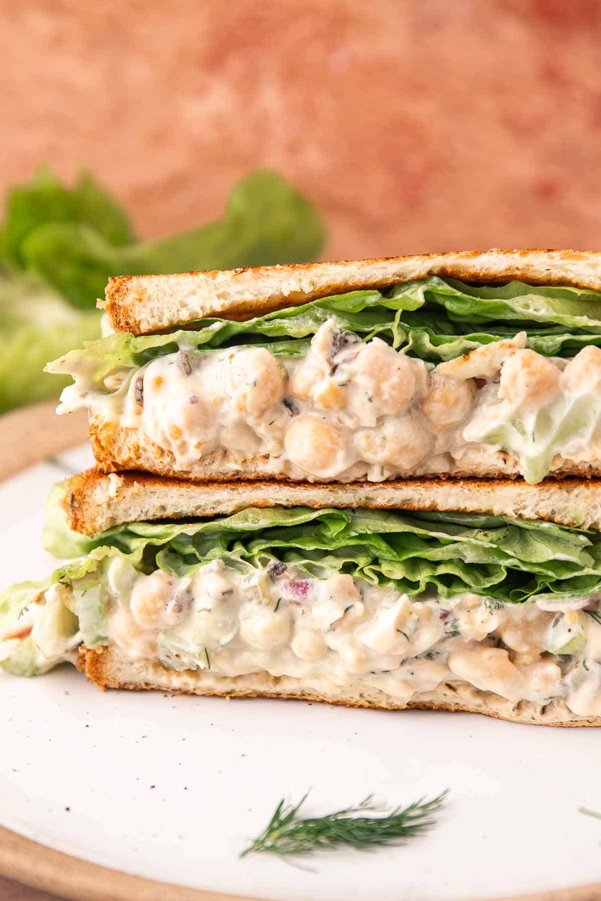Close-up side view of creamy chickpea salad sandwich with crisp lettuce layers