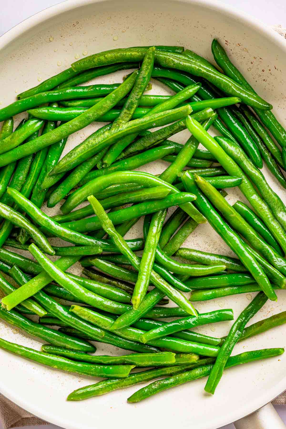 Fresh green beans cooking in a skillet until bright green and lightly blistered