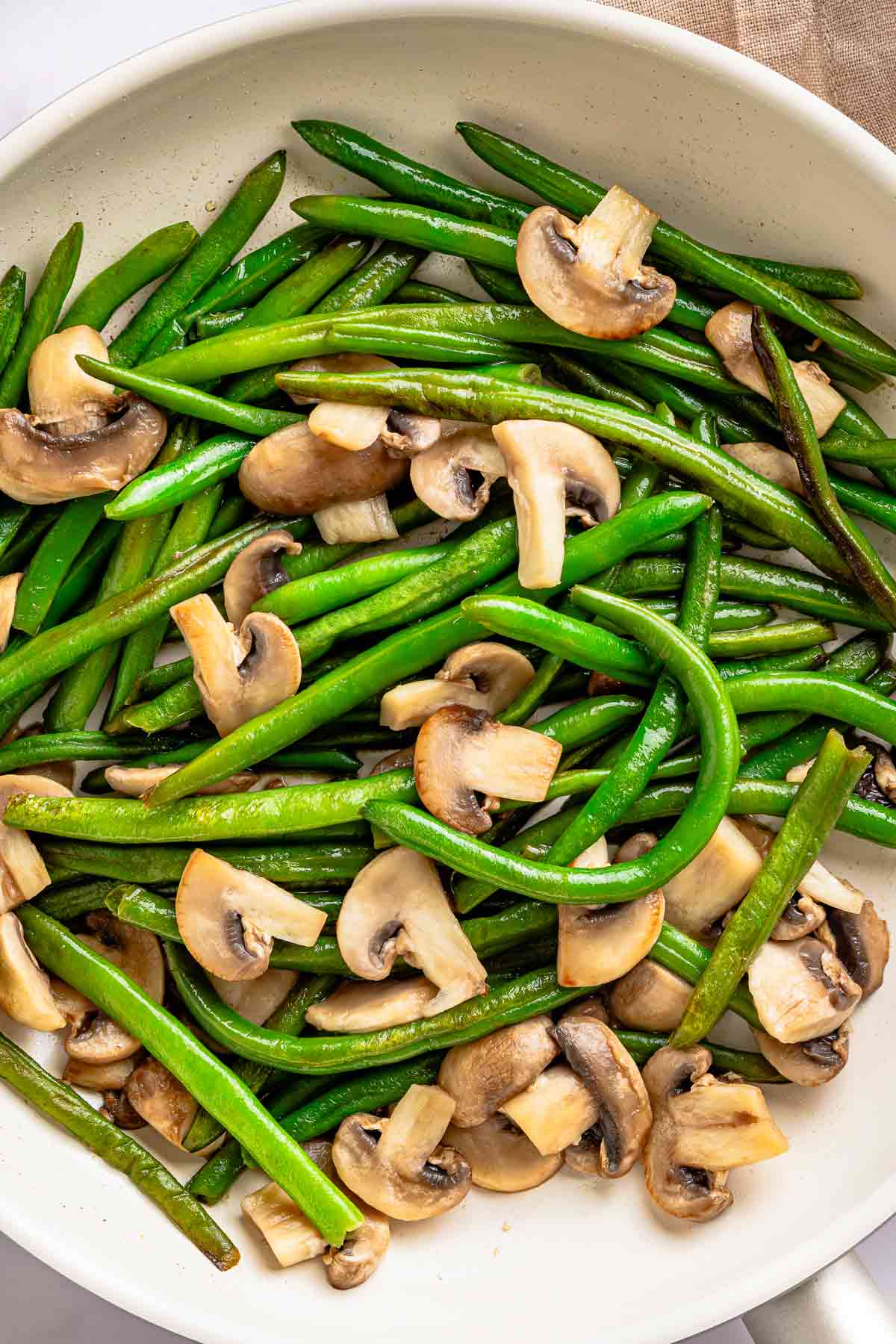 Green beans and mushrooms cooking together in a skillet before adding the sauce