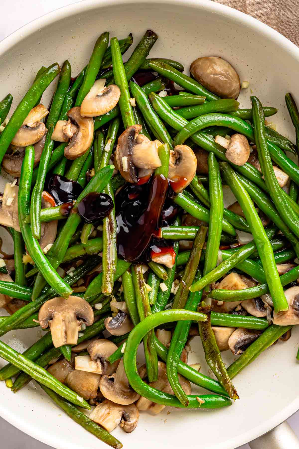 Soy sauce mixture poured over green beans and mushrooms in a skillet