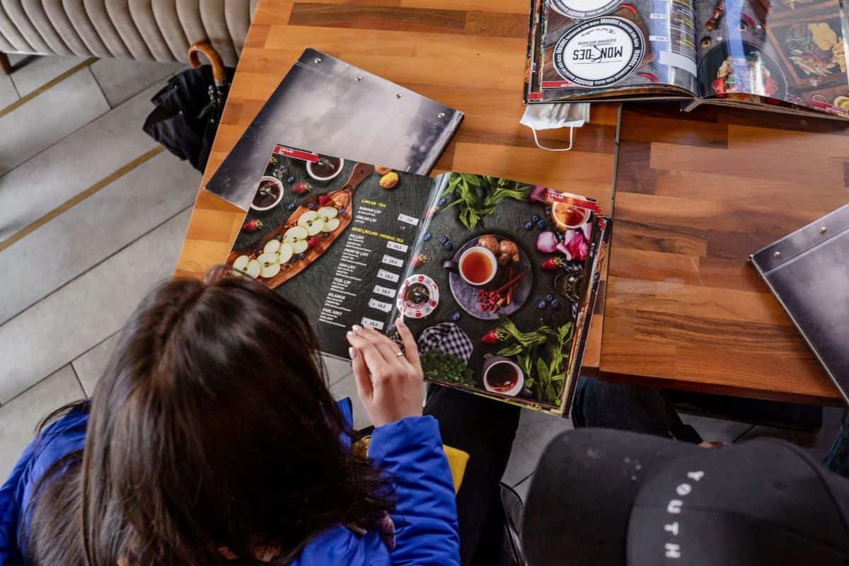 Person reading a restaurant menu while choosing a meal