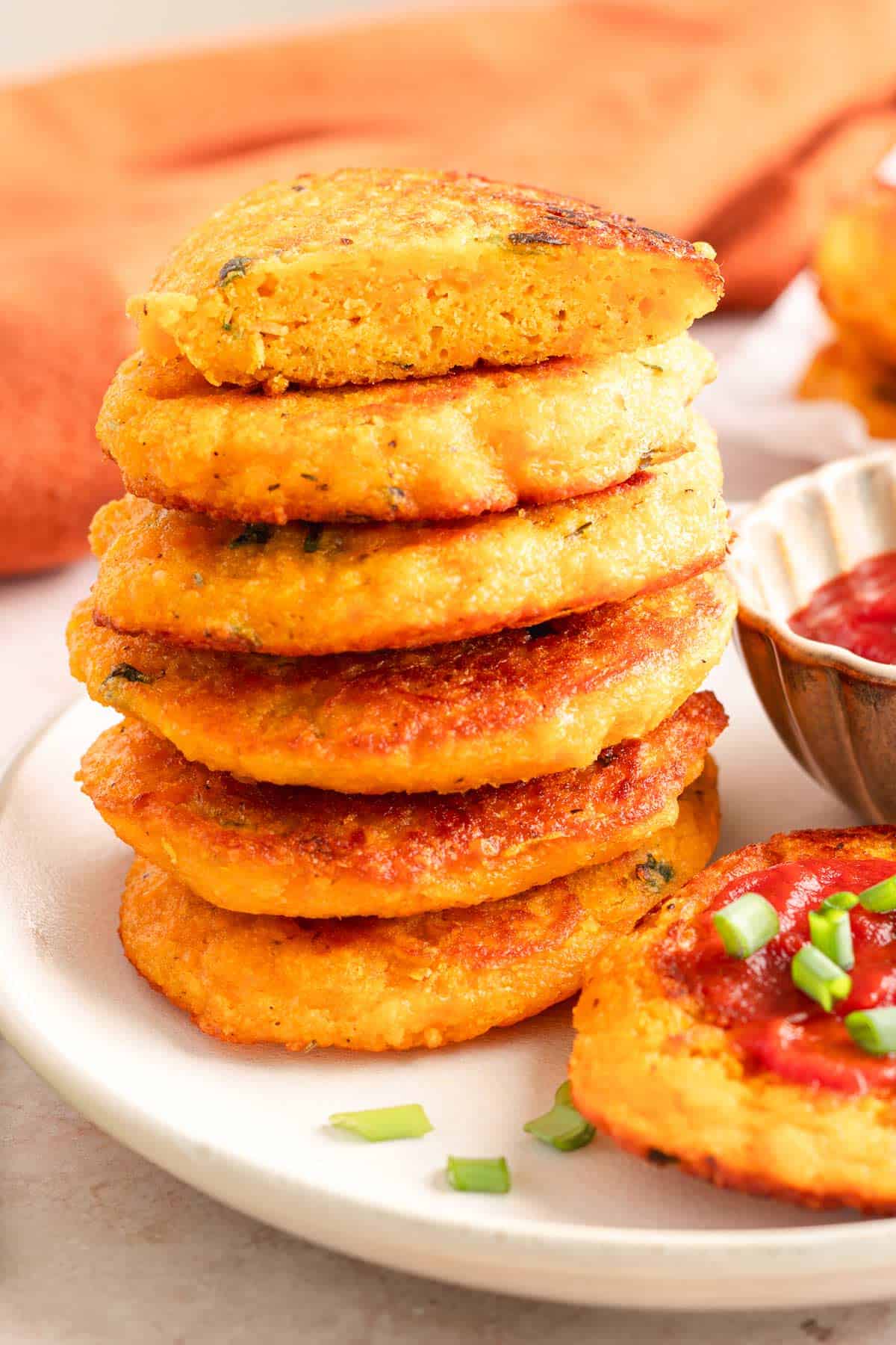 Stack of crispy sweet potato lentil fritters on a white plate