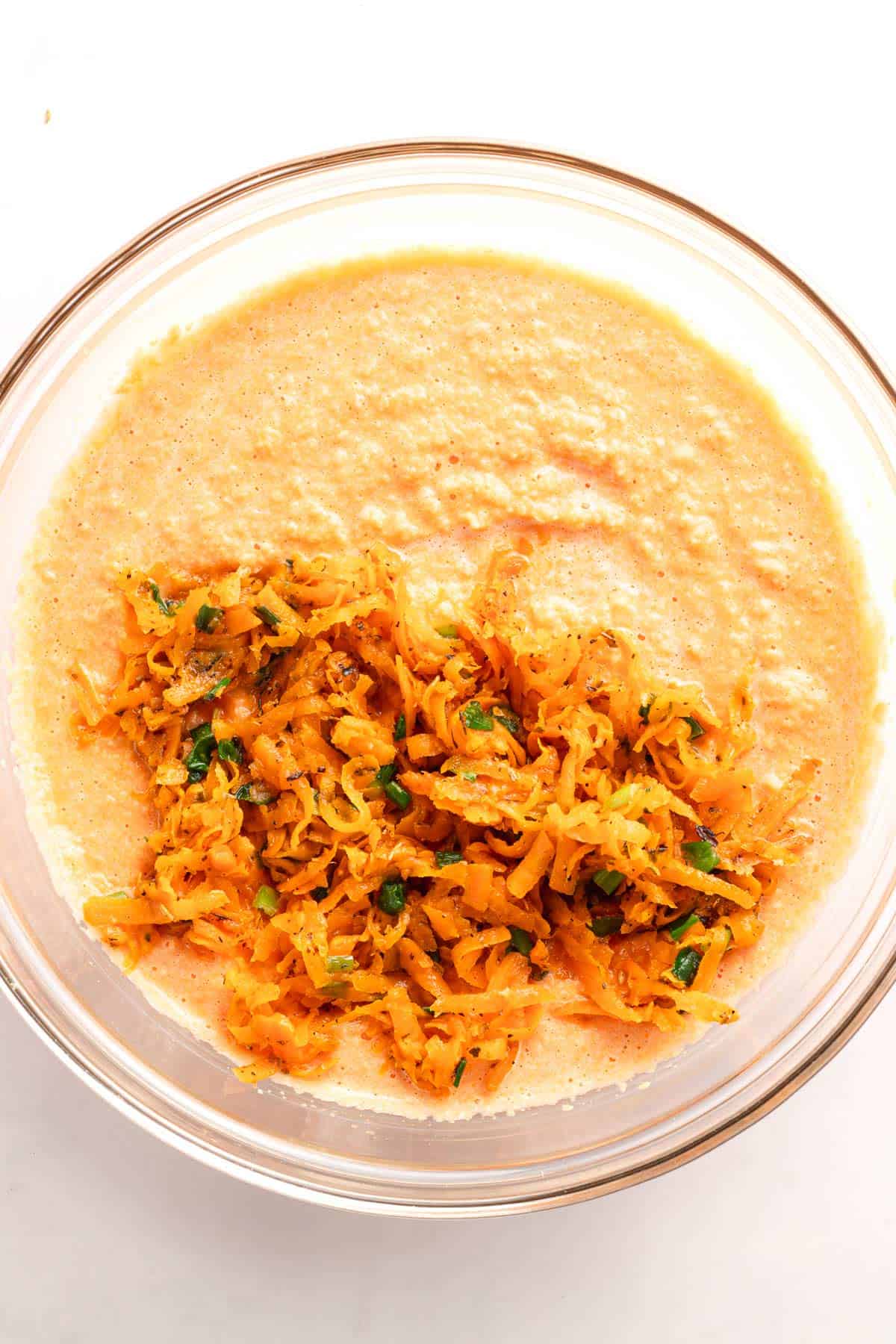 Sweet potato mixture added to smooth lentil batter in a glass bowl