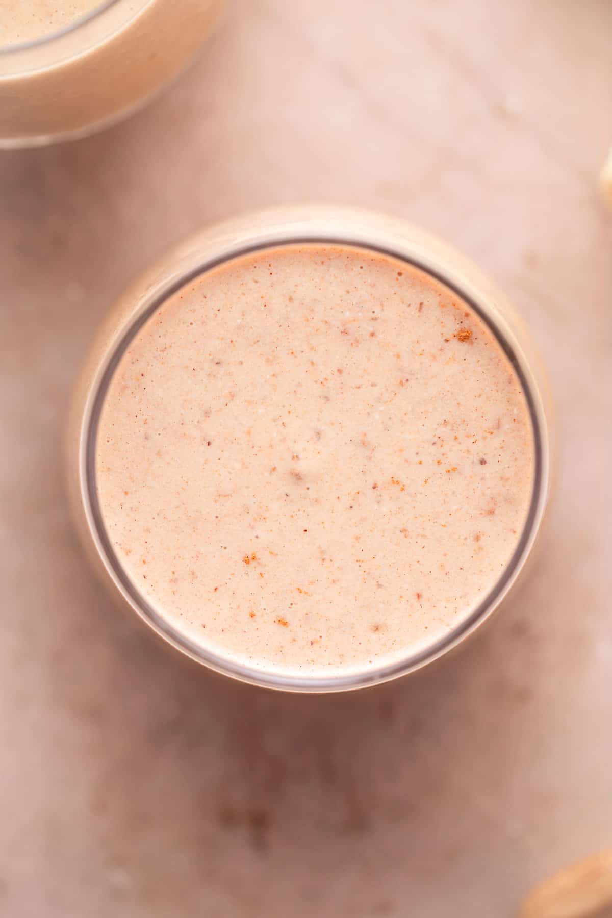 Top view of a creamy vanilla date smoothie in a clear glass.