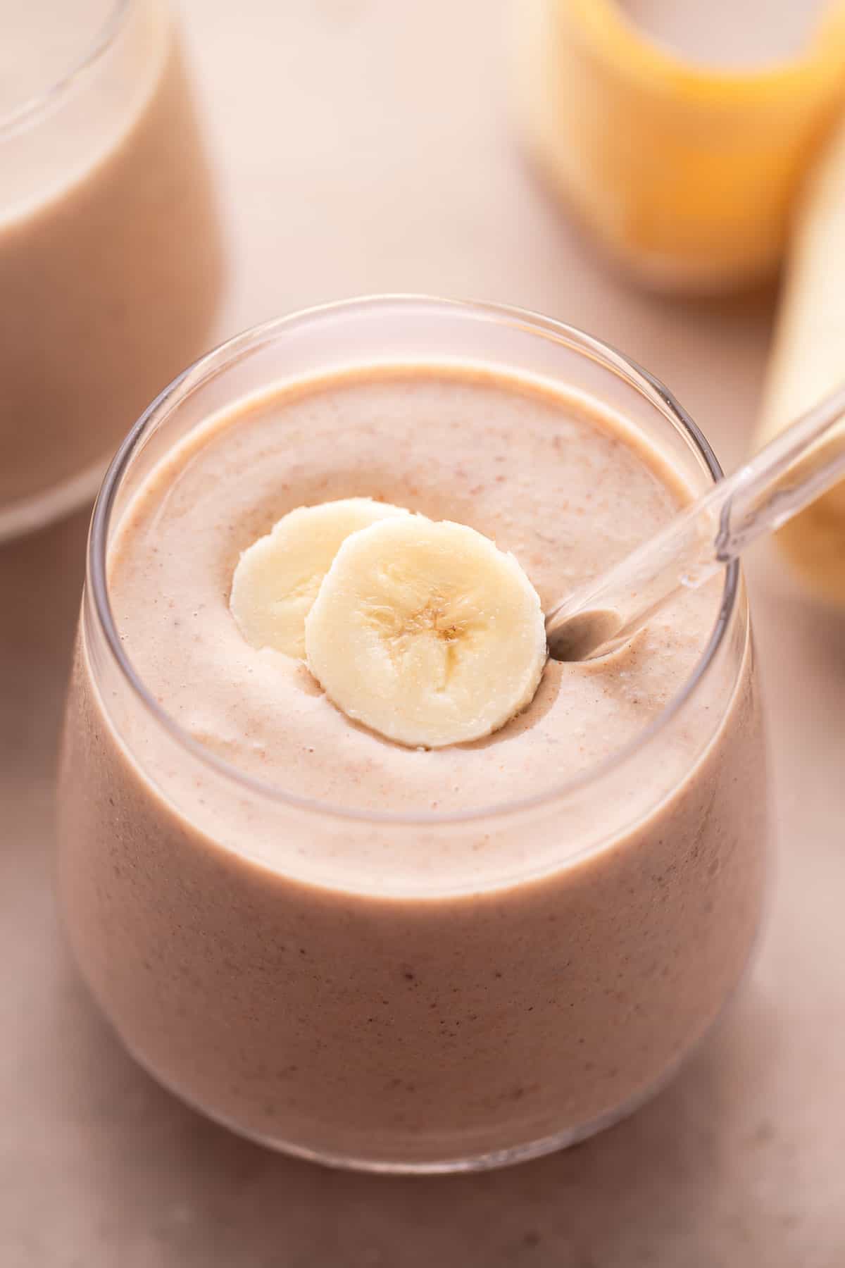 Close-up of a creamy vanilla date smoothie with banana slices on top.