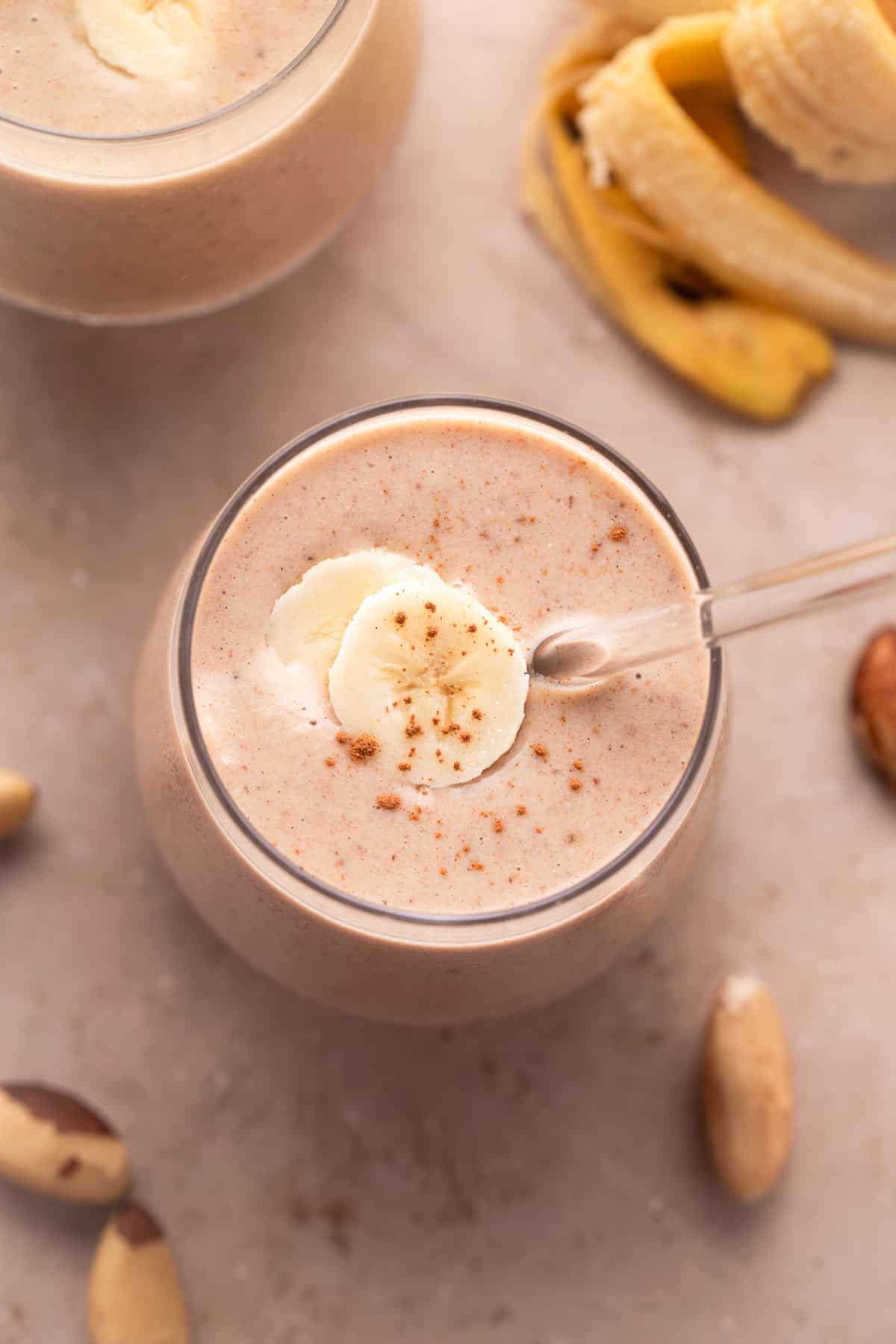Glass of creamy vanilla date smoothie topped with a banana slice and cinnamon.