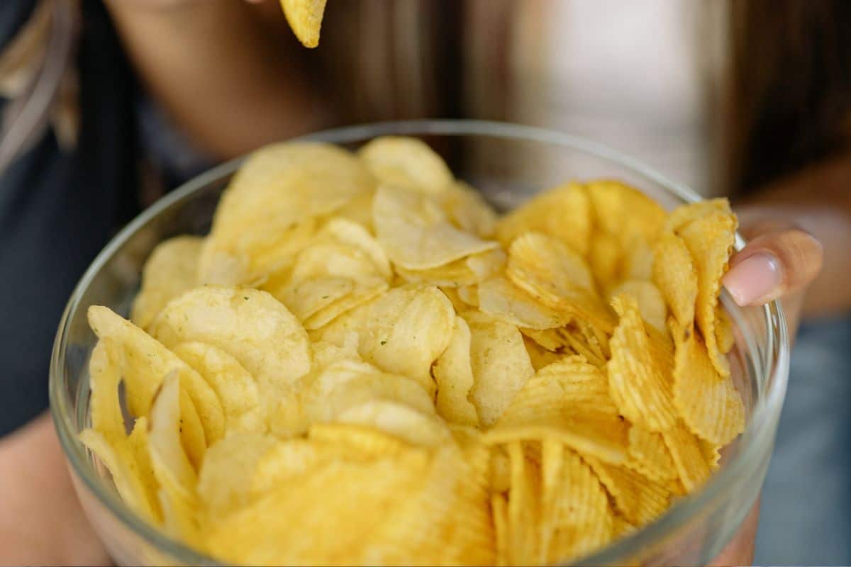 Potato chips served in a clear glass bowl.