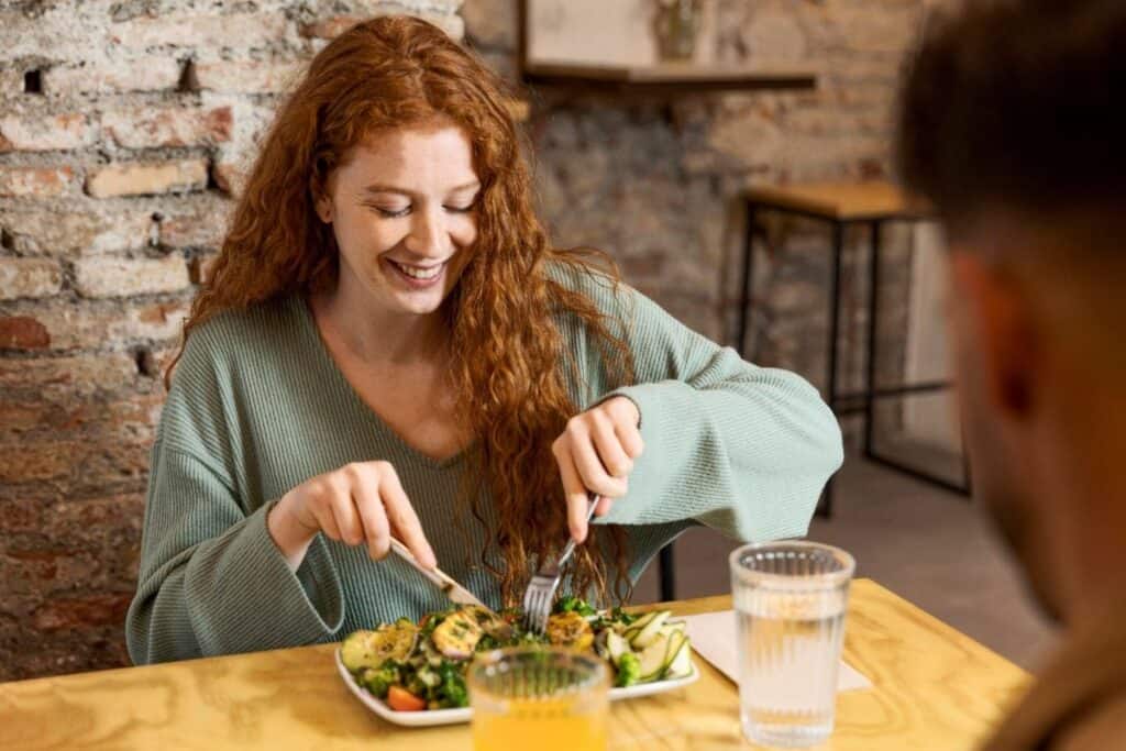 Woman eating a plant-based meal at a restaurant table.