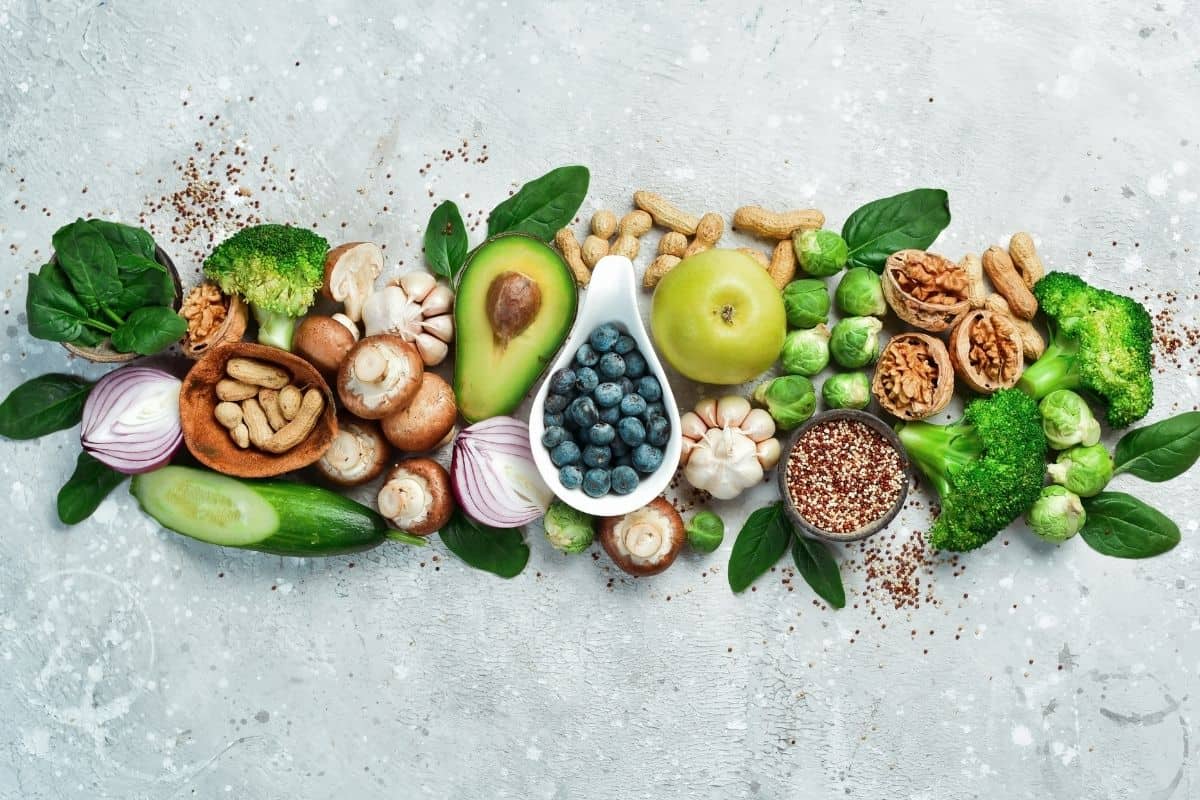 Assortment of nutrient-rich foods including avocado, berries, broccoli, nuts, mushrooms, and leafy greens.