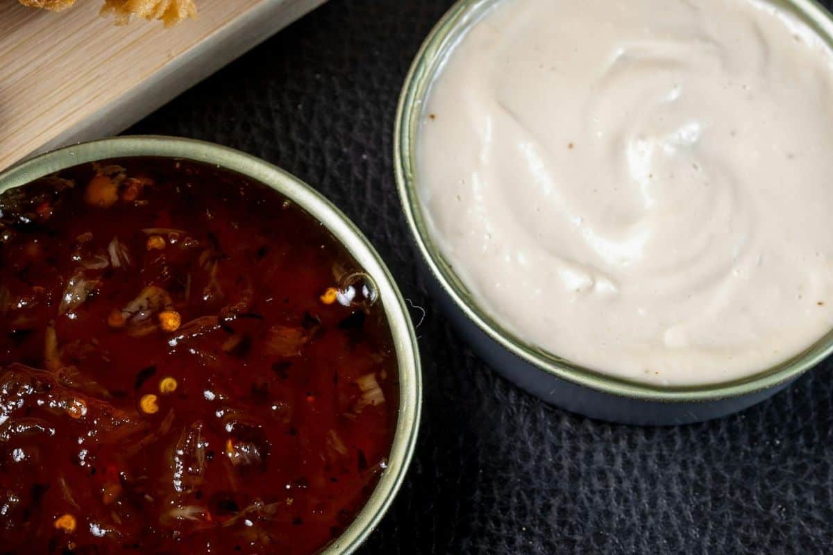 Two bowls of condiments, one red sauce and one creamy white sauce.